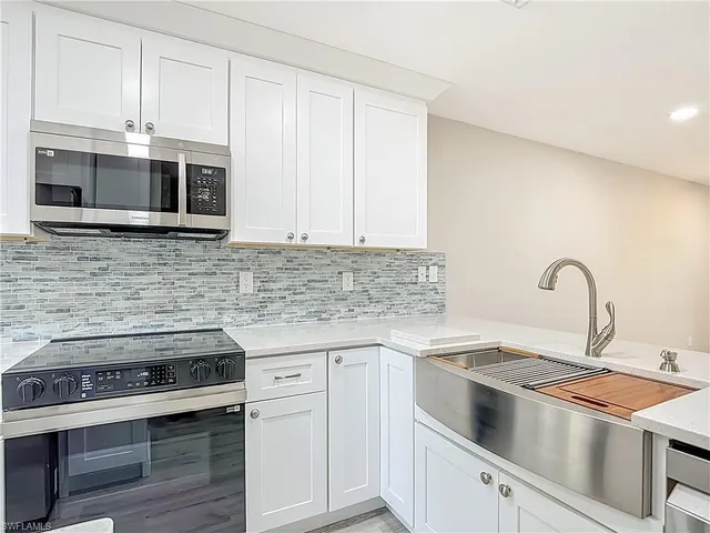 a kitchen with stainless steel appliances granite countertop grey cabinets a stove a sink and dishwasher