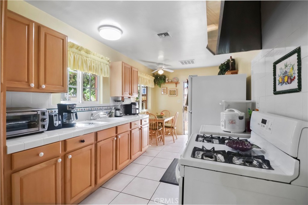 9206 Rendalia Street Bellflower, CA 90706 - Photo 12 of 27 a kitchen with stainless steel appliances a stove a sink and a refrigerator