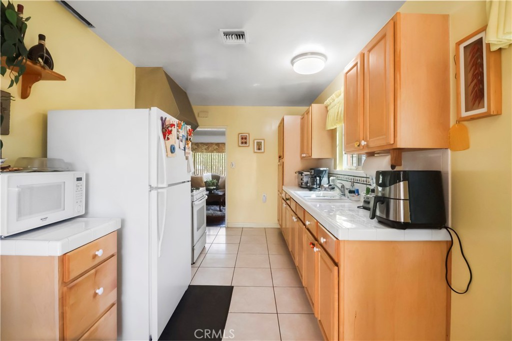 9206 Rendalia Street Bellflower, CA 90706 - Photo 13 of 27 a kitchen with a refrigerator a stove top oven and cabinets