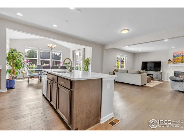 a open kitchen with stainless steel appliances granite countertop a living room and couches with wooden floor