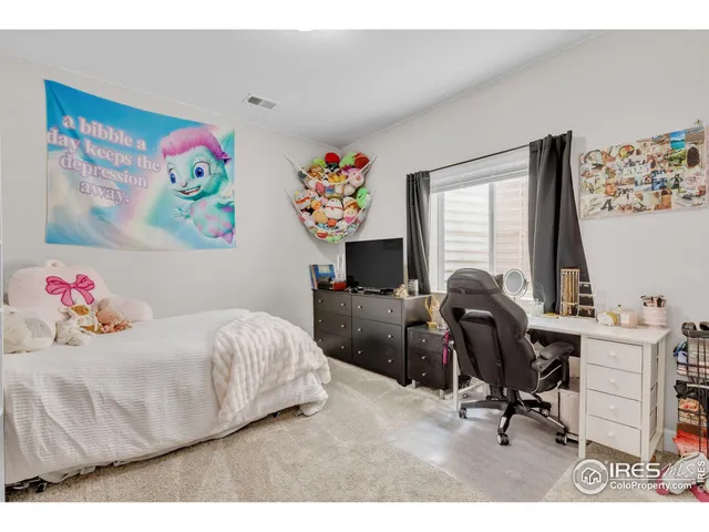 a bedroom with a bed a desk and painting on the wall
