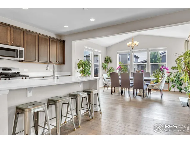 a kitchen with stainless steel appliances granite countertop a table chairs and a refrigerator
