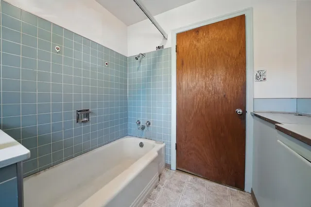 a bathroom with a granite countertop bathtub shower and sink