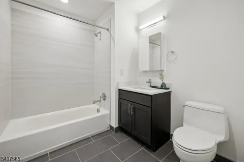 a bathroom with a bathtub shower sink vanity and toilet