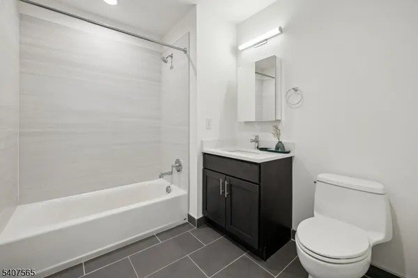 a bathroom with a bathtub shower sink vanity and toilet