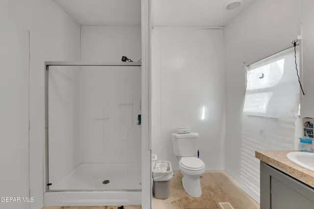a bathroom with a granite countertop sink a toilet and a shower