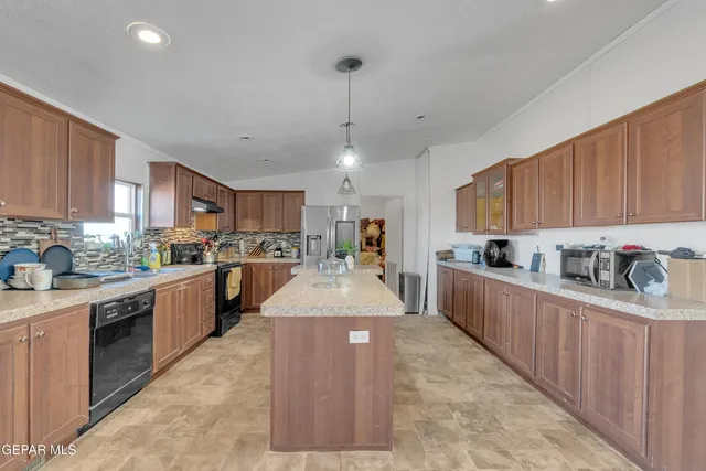 a large kitchen with stainless steel appliances granite countertop a stove top oven a sink a center island and cabinets