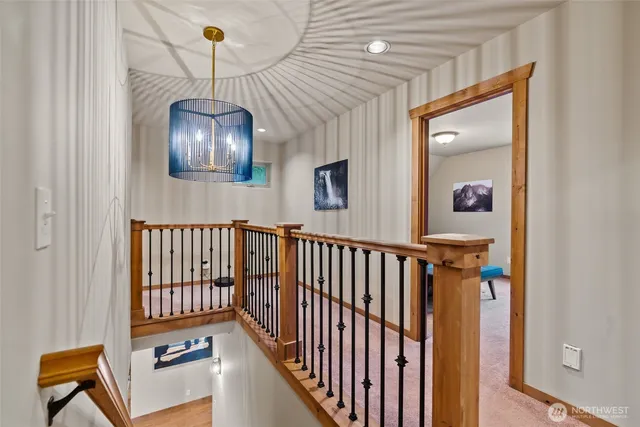 a view of a hallway with wooden floor and chandelier