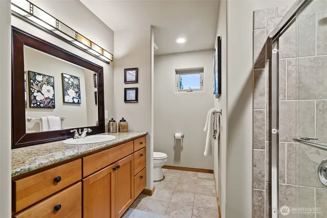 a bathroom with a granite countertop sink toilet and painting on the wall