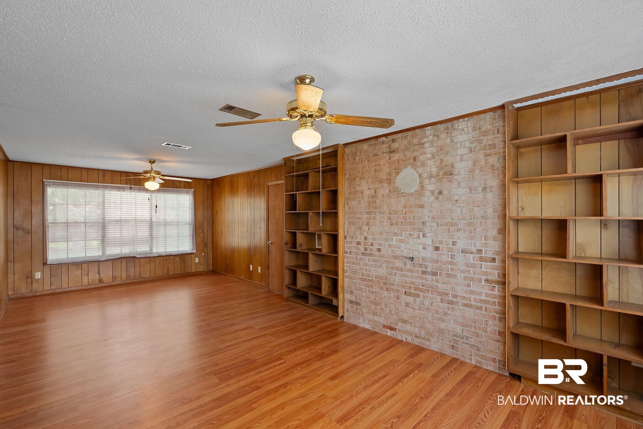 716 North Cedar Street Foley, AL 36535 - Photo 13 of 25 Spacious interior featuring wood-finish flooring, wood paneling, and an exposed brick accent wall