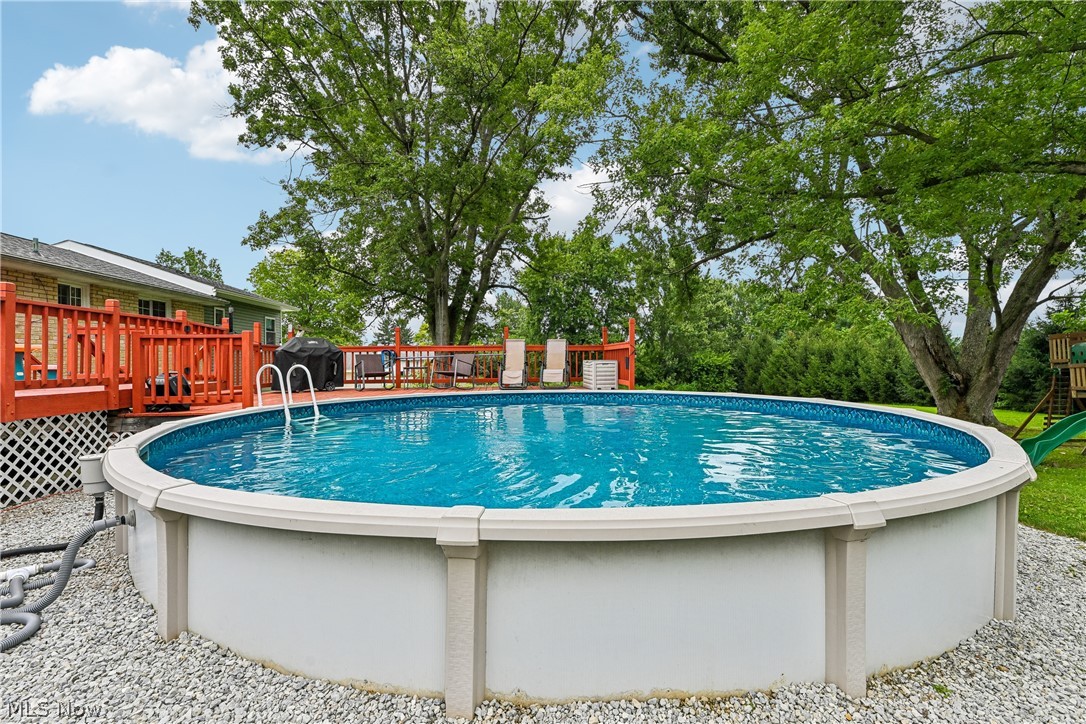 15111 Mt Eaton Road North Rittman, OH 44270 - Photo 37 of 50 Expansive backyard featuring an above-ground pool, gravel surround, and a sizable wooden deck with lattice skirting
