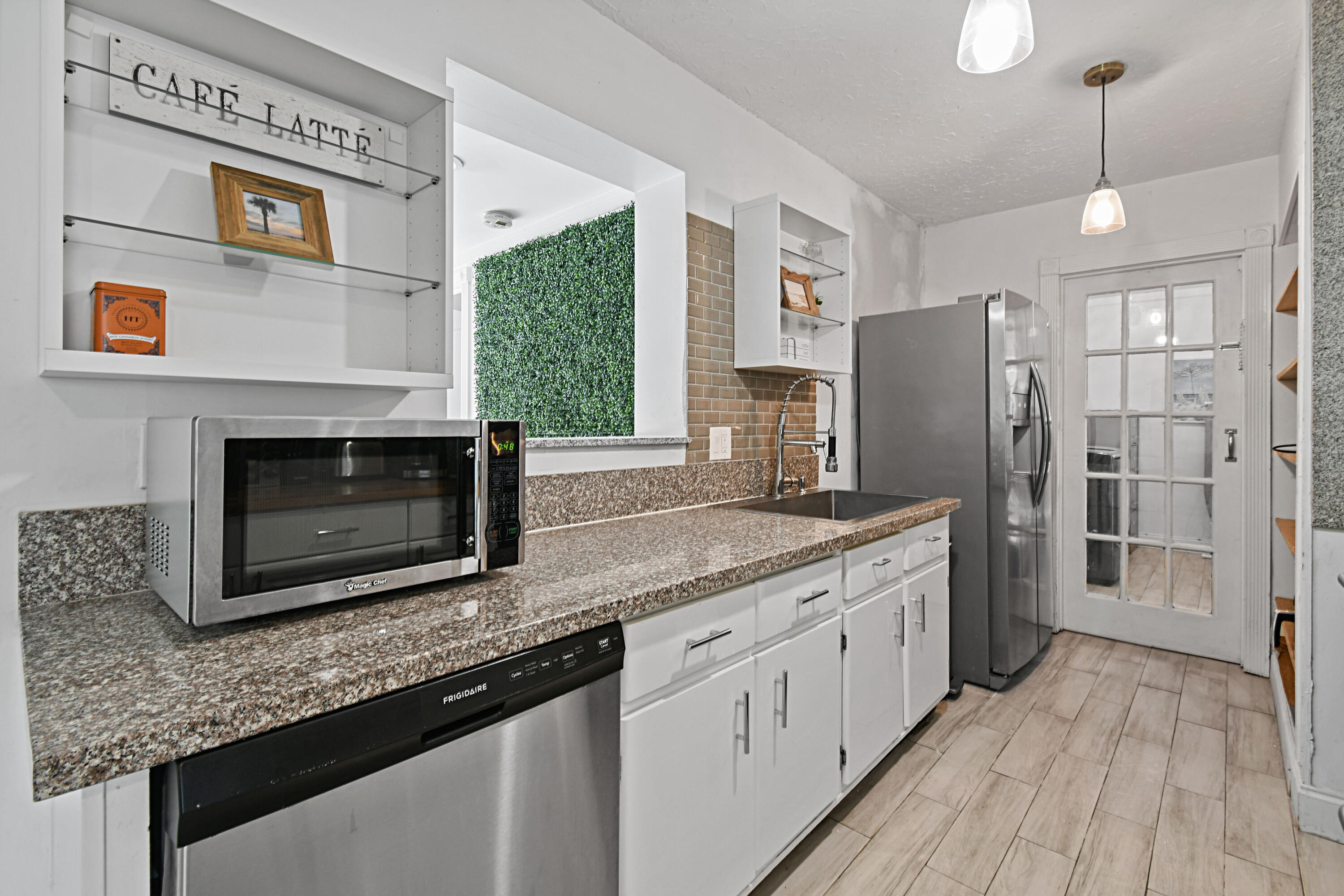 973 Laurel Road North Palm Beach, FL 33408 - Photo 15 of 57 a kitchen with stainless steel appliances granite countertop a refrigerator a stove and a wooden floors