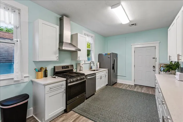 a kitchen with stainless steel appliances granite countertop a stove a sink dishwasher a refrigerator and a dining table with wooden floor