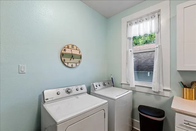 a view of washer and dryer with bathroom in the background