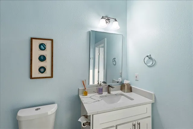 a bathroom with a toilet sink vanity and mirror