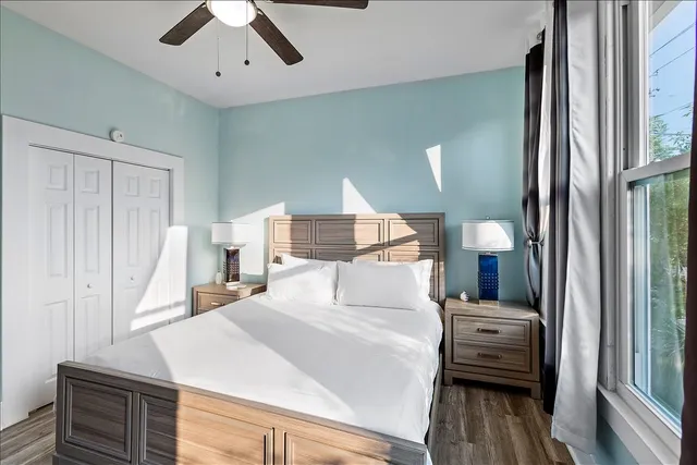 a bedroom with a bed and a large window with wooden floor