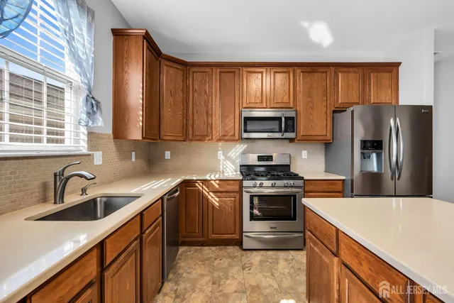 a kitchen with stainless steel appliances granite countertop a stove a sink a refrigerator and a microwave