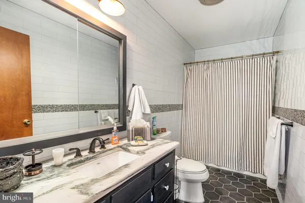 a bathroom with a granite countertop sink toilet and mirror