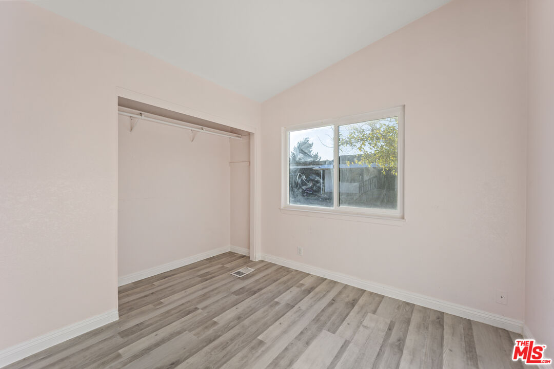 6677 Maricopa Road Phelan, CA 92371 - Photo 11 of 38 a view of an empty room with wooden floor and a window