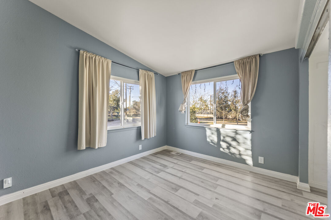 6677 Maricopa Road Phelan, CA 92371 - Photo 13 of 38 a view of an empty room with wooden floor and a window
