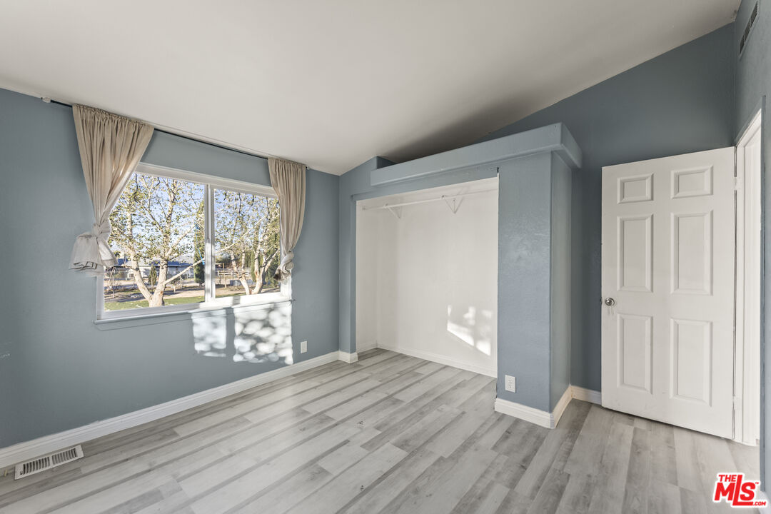 6677 Maricopa Road Phelan, CA 92371 - Photo 14 of 38 a view of an empty room with wooden floor and a window