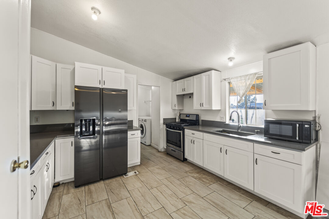 6677 Maricopa Road Phelan, CA 92371 - Photo 23 of 38 a kitchen with granite countertop a sink stainless steel appliances and white cabinets