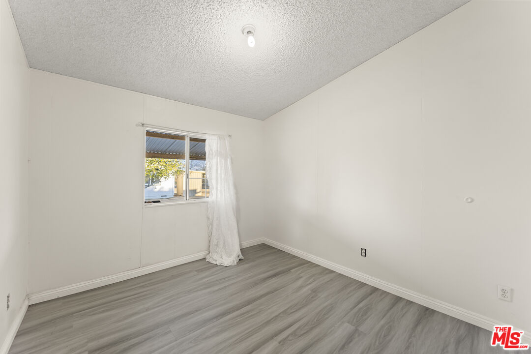 6677 Maricopa Road Phelan, CA 92371 - Photo 30 of 38 a view of an empty room with wooden floor and a window