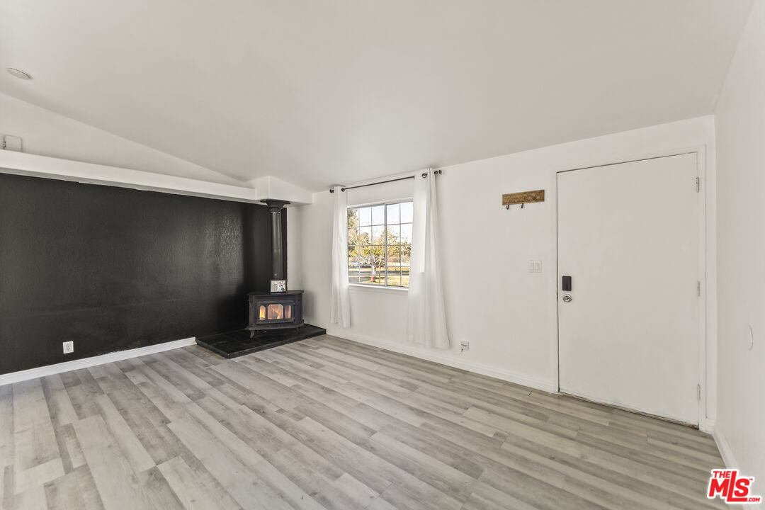6677 Maricopa Road Phelan, CA 92371 - Photo 6 of 38 a view of an empty room with wooden floor and a window
