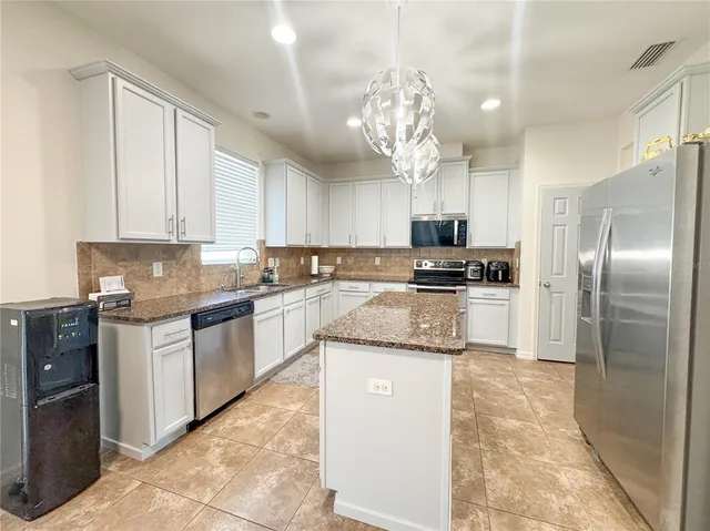 a kitchen with granite countertop stainless steel appliances a sink dishwasher a refrigerator a stove top oven and cabinets