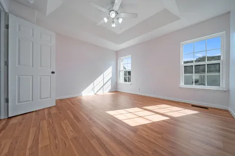 a view of empty room with wooden floor and fan