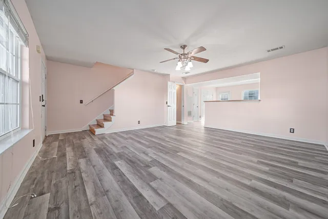 a view of empty room with wooden floor and fan