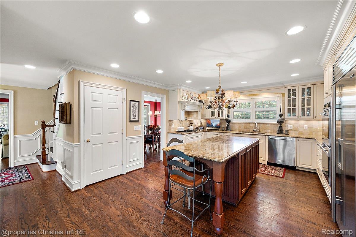 135 Clifton Road Bloomfield Hills, MI 48301 - Photo 20 of 77 Spacious kitchen featuring a large central island with a granite countertop, stainless steel appliances, cream cabinetry, and dark wood-finish flooring