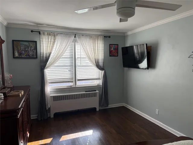 a view of an empty room with wooden floor and windows