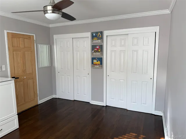 an empty room with wooden floor closet and windows