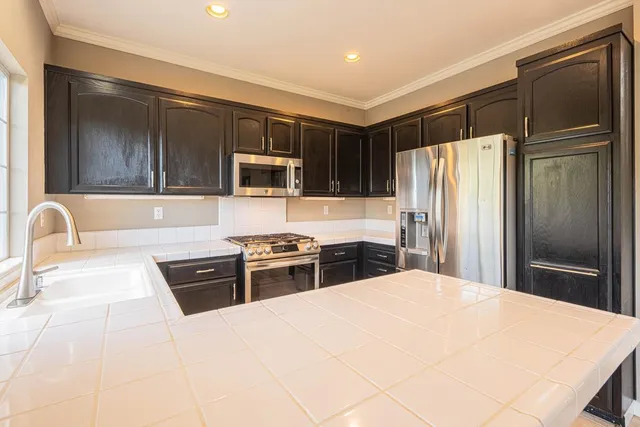 a kitchen with granite countertop a refrigerator stove top oven and sink