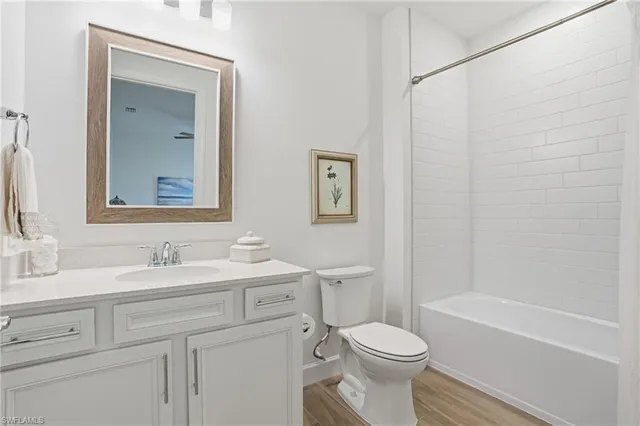 a bathroom with a toilet sink vanity tub and mirror