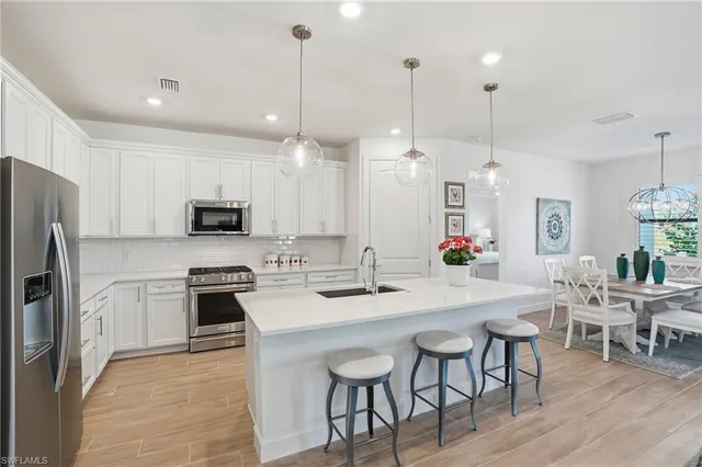 a kitchen with stainless steel appliances kitchen island granite countertop a table chairs stove and refrigerator