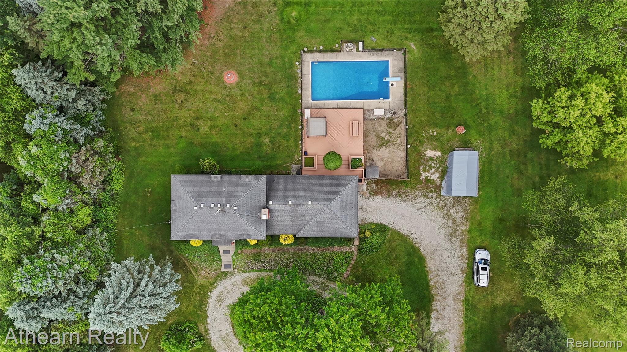 12427 Foley Road Fenton, MI 48430 - Photo 17 of 47 Expansive property featuring an in-ground swimming pool with surrounding concrete and deck areas, a private gravel drive, a detached storage building, and mature trees providing natural screening