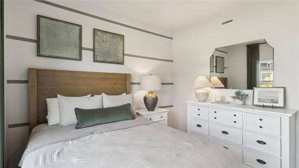 a bedroom with a bed a mirror and lamp on dresser