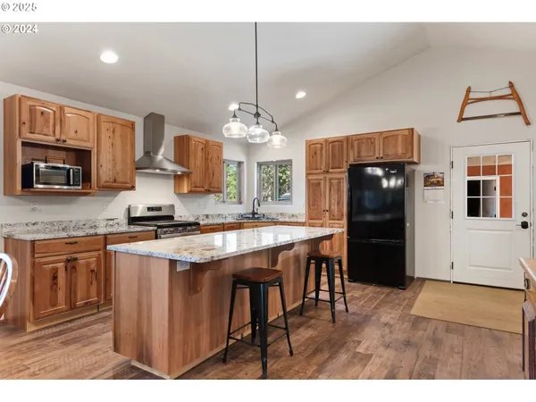 a kitchen with stainless steel appliances granite countertop a refrigerator a stove a sink a dining table and chairs