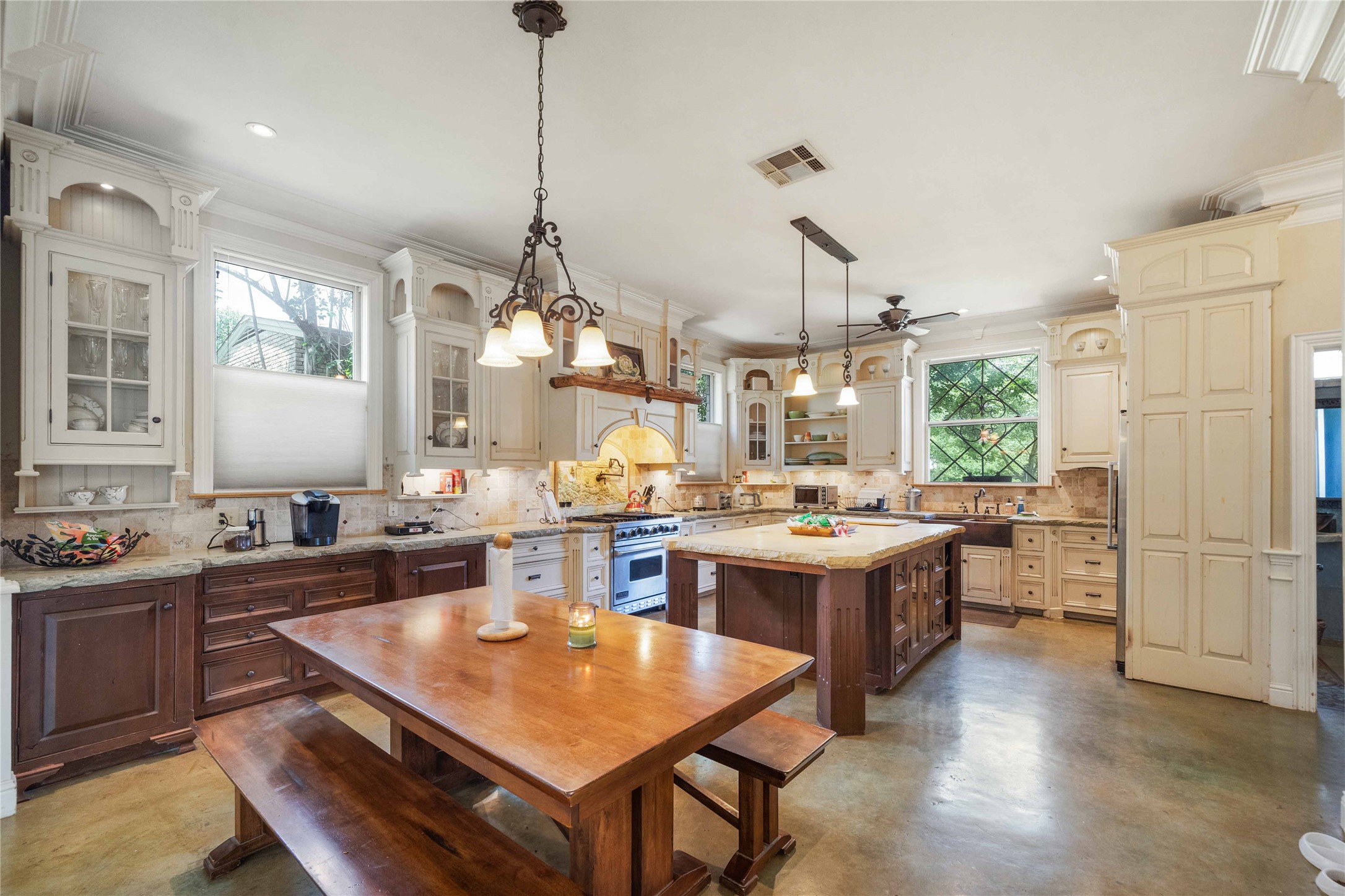 Two tone kitchen featuring two tone color scheme, concrete flooring, tasteful backsplash, hanging light fixtures, and light stone counters