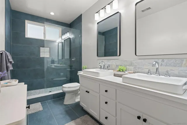 a bathroom with a double vanity sink toilet and shower