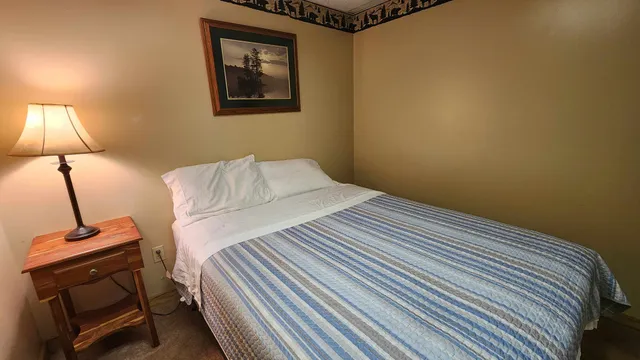 a bedroom with a bed and a lamp with the wooden floor