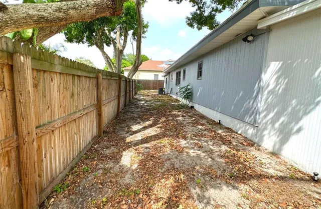 a view of a yard with wooden fence and a large tree