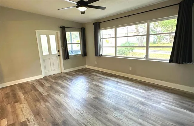 a view of an empty room with wooden floor and a window