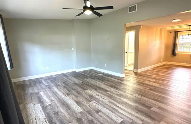 an empty room with wooden floor and windows