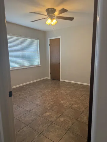 a view of an empty room with window and chandelier fan