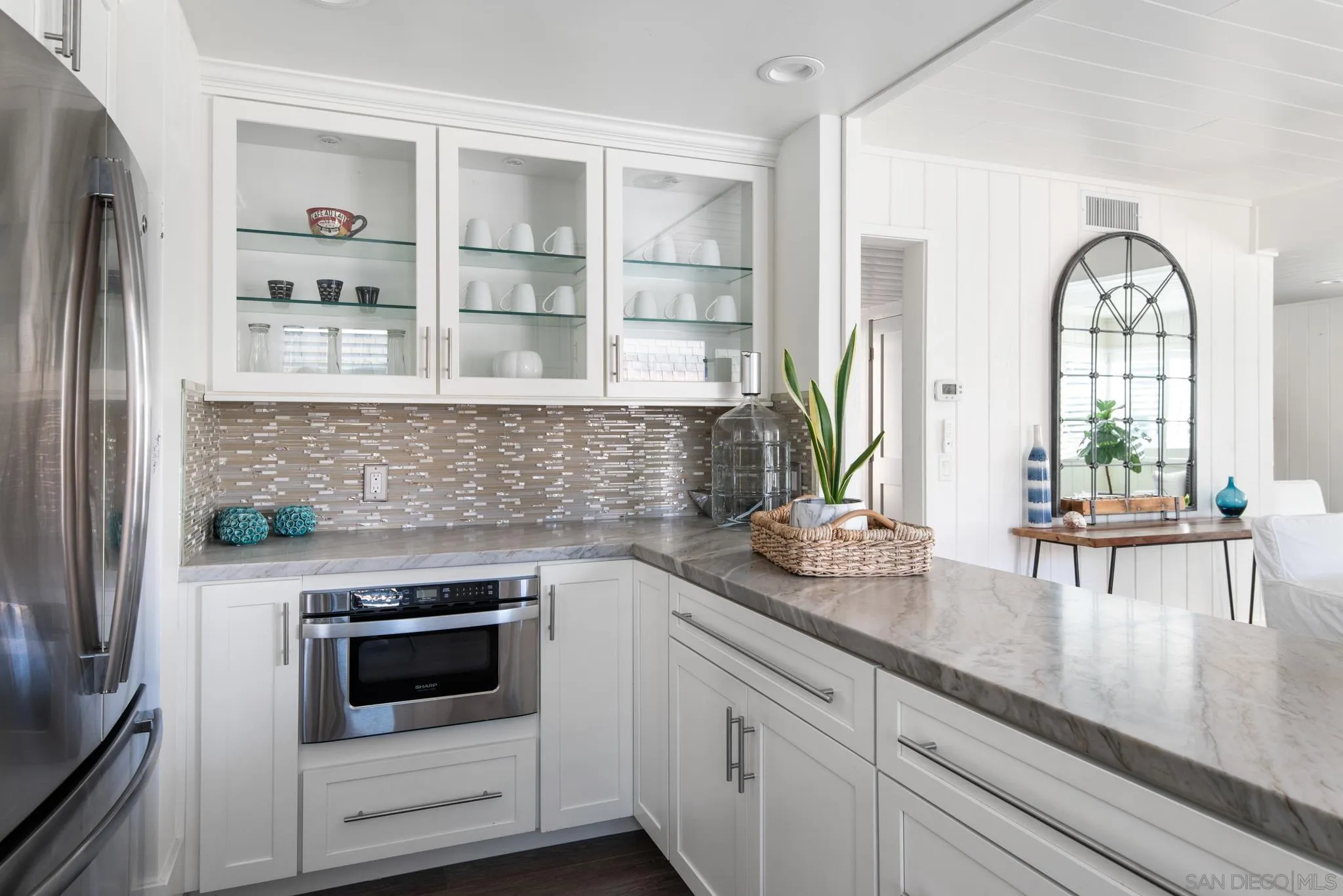 1933 Coast Boulevard Del Mar, CA 92014 - Photo 22 of 47 a kitchen with stainless steel appliances a white counter top space a large window and cabinets