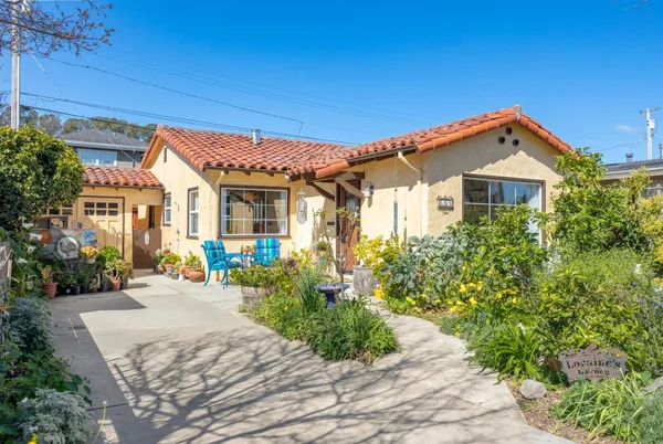a front view of a house with a yard and potted plants