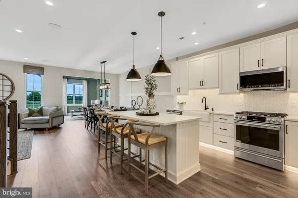 a kitchen with stainless steel appliances a dining table chairs stove and white cabinets